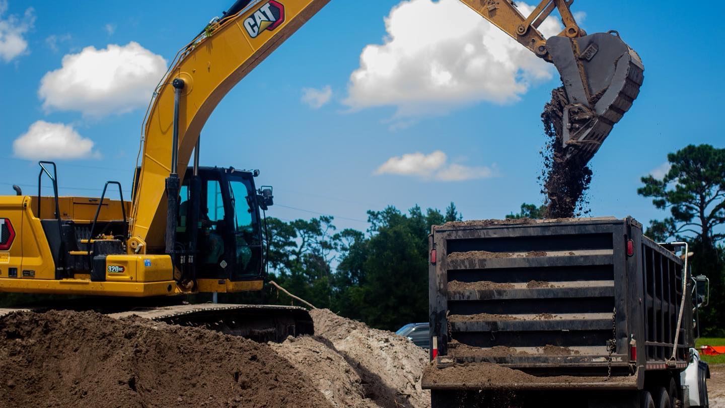 CAT excavator loading dirt on a land clearing job site in Central Florida