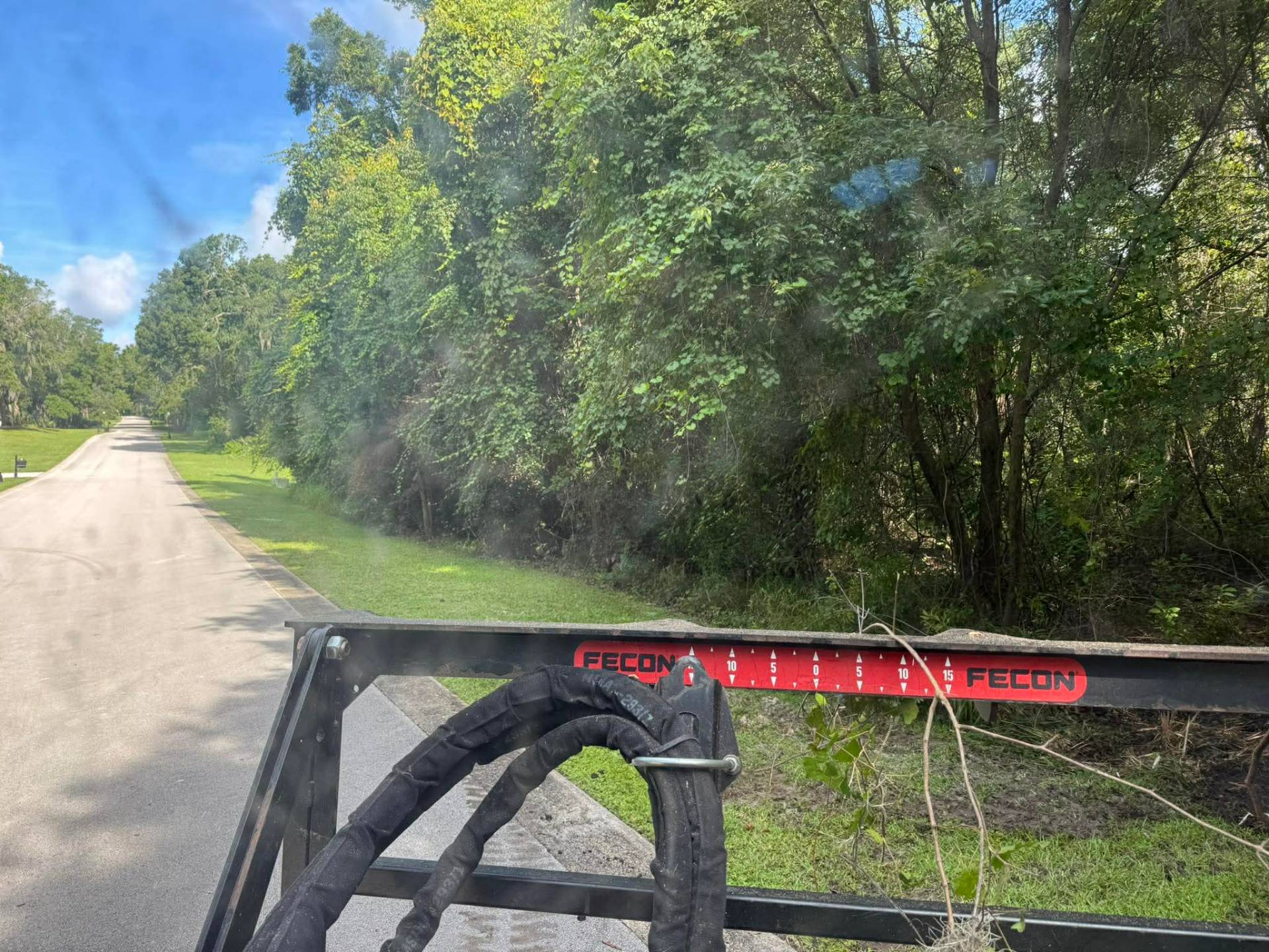 Fecon mulcher attachment on trailer approaching overgrown roadside vegetation in Volusia County, FL