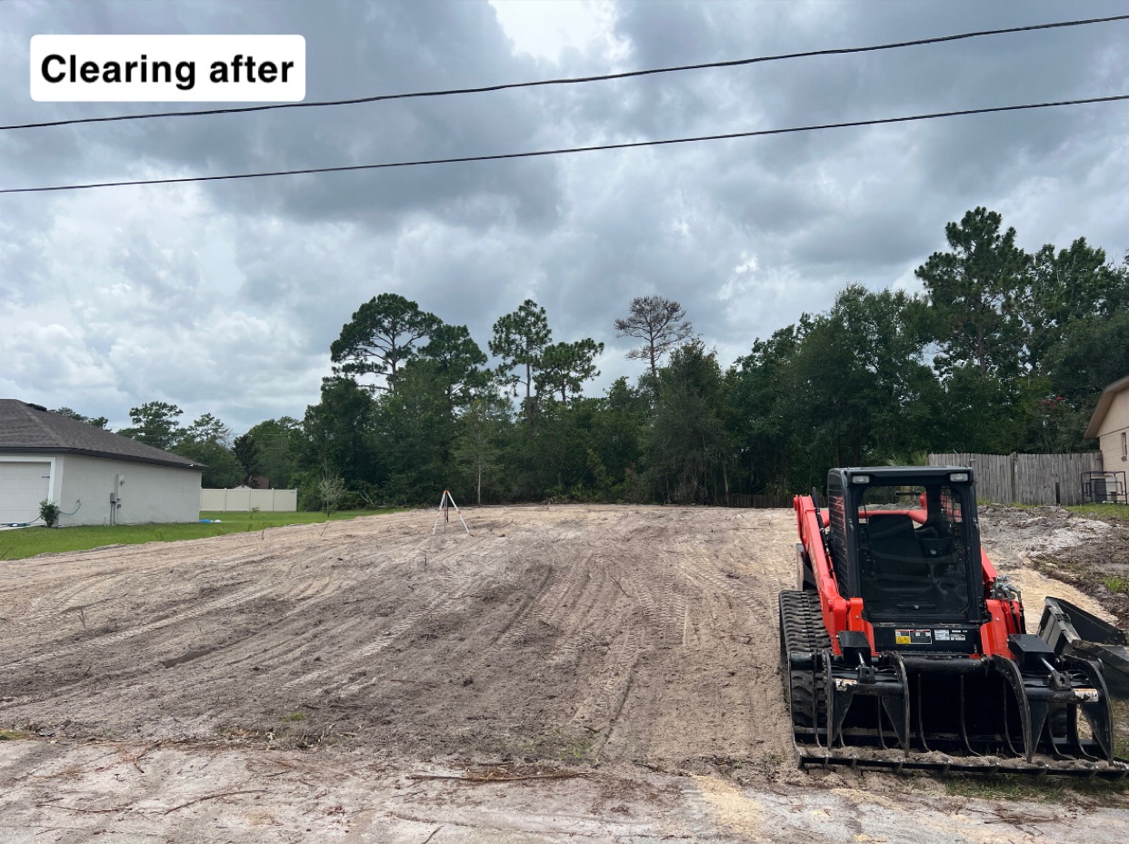 After land clearing — clean graded lot with Kubota skid steer and homes visible in Deltona, FL