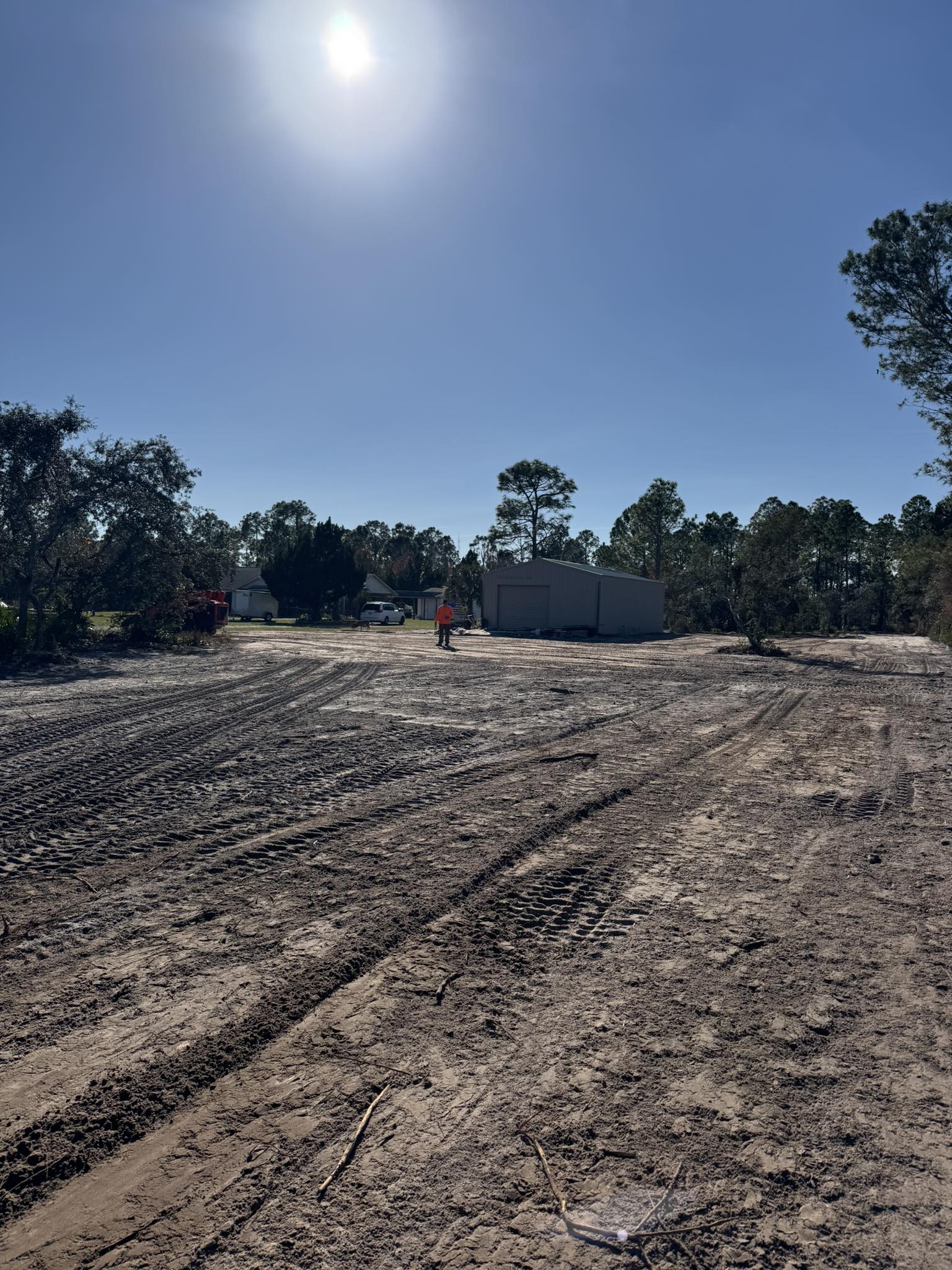 Worker walking across freshly cleared lot with metal building and equipment in Deltona, FL